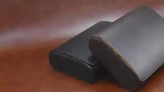 Open brown watch case with five watches displayed on a wooden surface.