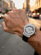 Man wearing TOMI T029 Opulence Radiance watch with silver diamond-set case and black leather strap, city street background