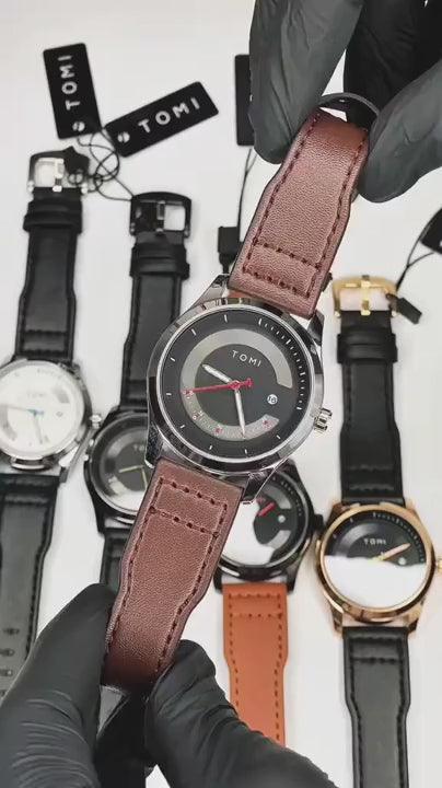 TOMI T099 Perpetual Icon watch with brown leather strap, held in hand with other TOMI watches