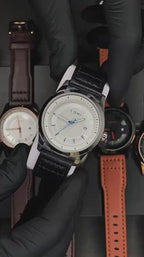 TOMI T099 Perpetual Icon watch with white dial and black leather strap, held in hand with other TOMI watches