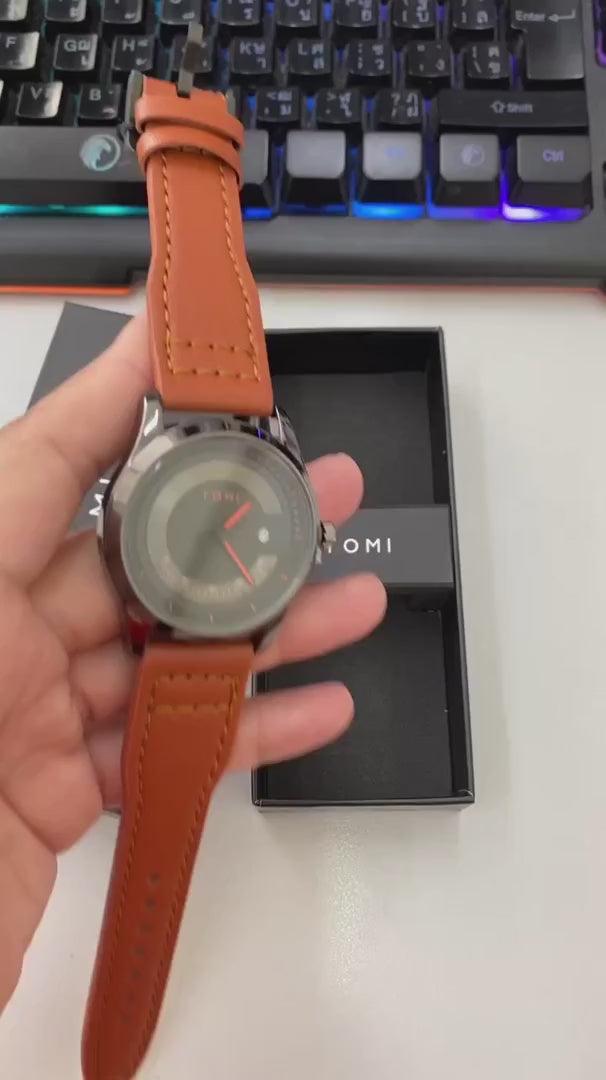 TOMI T099 Perpetual Icon watch with black dial and orange leather strap, held in hand